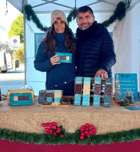 Ana y Juan posan con los turrones de chocolate Canayas en un mercado de diciembre.